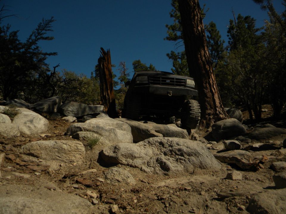 Black 1992 Ford Bronco driving over rocks on a trail