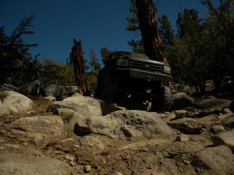 Dark 1992 Ford Bronco climbing over rocks on a trail
