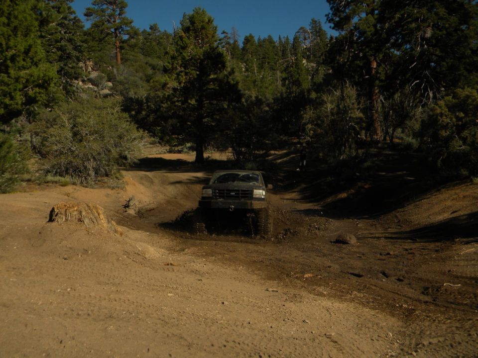 1992 Ford Bronco driving through mud on an off-road trail