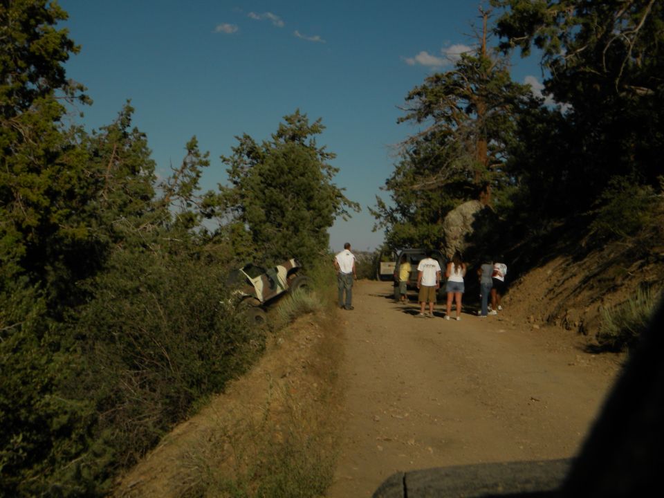 Off-road vehicles on a dirt road with people standing around