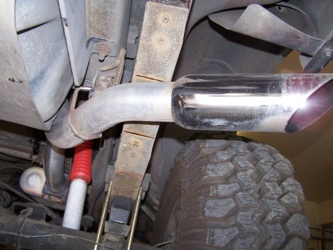 1989 Ford Bronco - Close-up view of a vehicle's exhaust system and suspension components, including a chrome-tipped muffler and leaf springs.