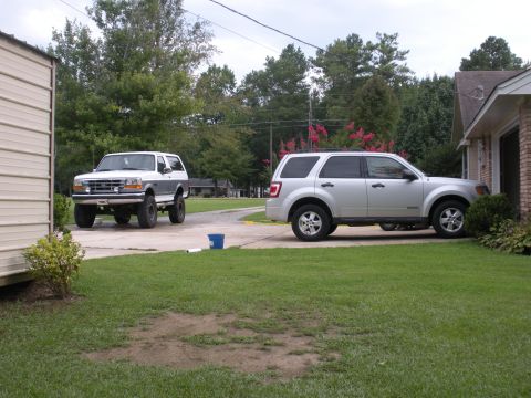 1995 Ford Bronco - A lifted 1995 Ford Bronco is parked in front of a building, with another SUV to its right.