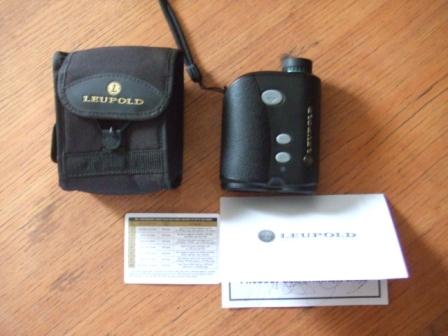 1996 Ford Bronco - A Leupold rangefinder, its carrying case, and documentation are laid out on a wooden table.