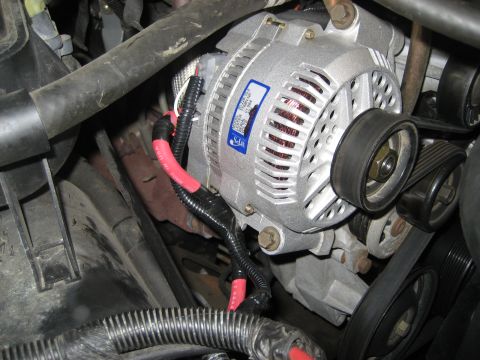 1996 Ford Bronco - Close-up view of a vehicle's alternator, showing wiring and a label with text.