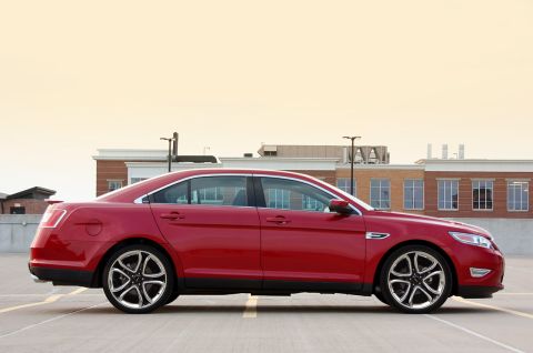 1993 Ford Taurus - Side profile of a red sedan with contemporary design elements and alloy wheels.