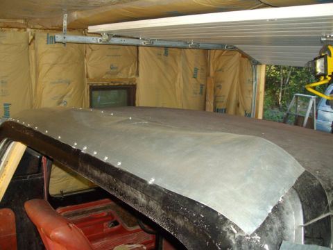 1978 Ford Bronco - The roof of a vehicle is undergoing repair work, with new metal sheeting being attached.