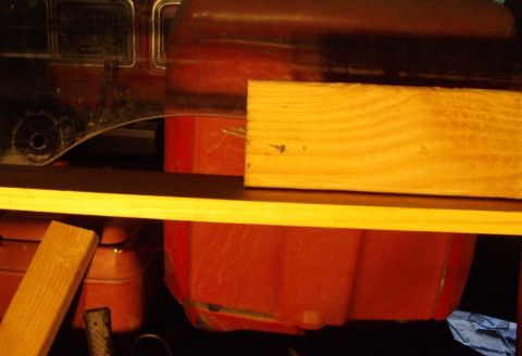 1978 Ford Bronco - A red vehicle part is partially obscured by wooden planks.