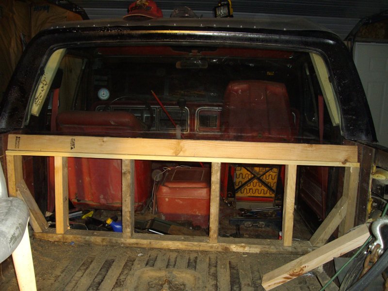 Wood-framed bulkhead built across the rear of a gutted black Bronco with red interior