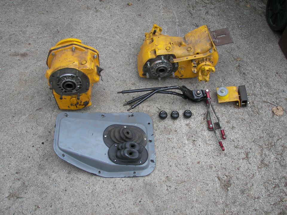 Yellow transfer case components and shifter linkage laid out on concrete