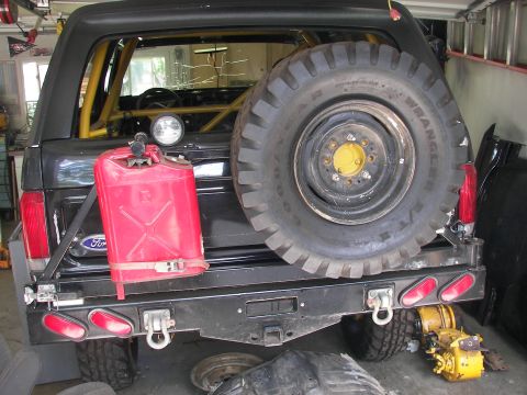 1988 Ford Bronco - Rear view of a black Ford Bronco with a spare tire mounted and a red jerry can on the bumper.