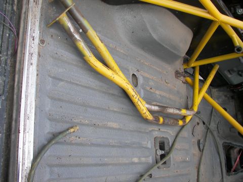 1988 Ford Bronco - The interior of a vehicle shows a roll cage and a green hose lying on the floor.