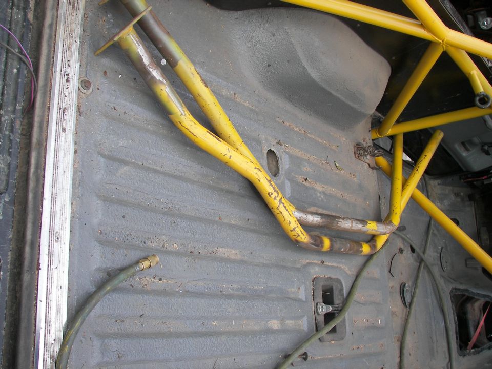 interior floor pan with yellow roll cage tubing and a green hose