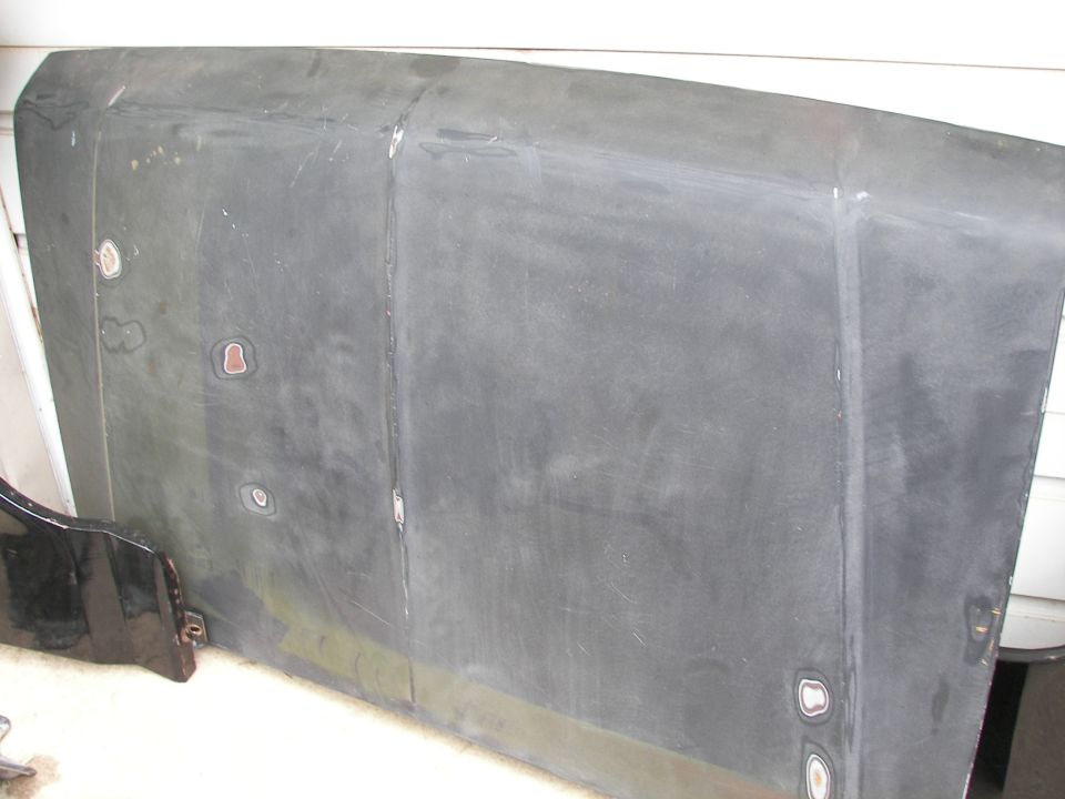 Gray hood with visible body filler and rust spots