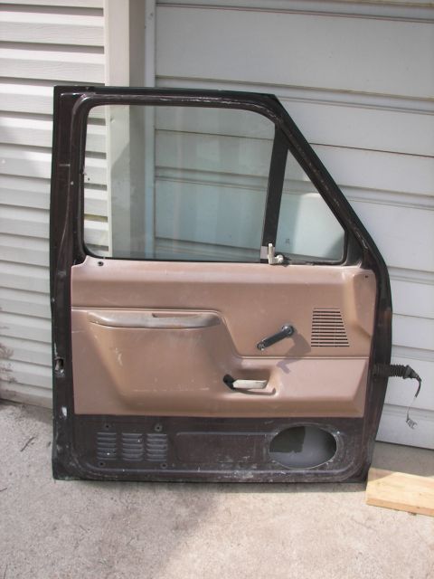 1988 Ford Bronco - A single car door, likely from an older model truck or SUV, is shown against a white paneled wall.
