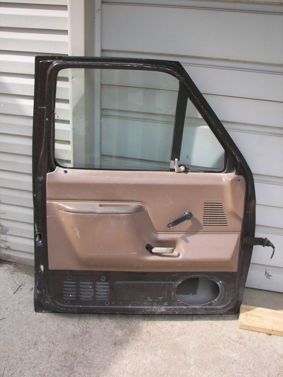 Brown and black car door with speaker cutout and vent