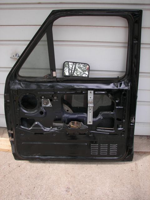 1988 Ford Bronco - This is the interior of a black vehicle door, revealing its internal components and a side mirror attached.