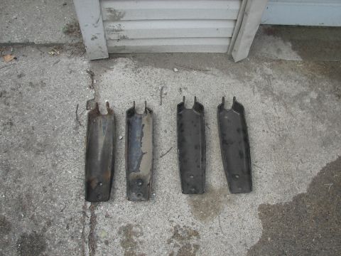 1988 Ford Bronco - Four metal brackets are laid out on a concrete surface, with a building in the background.