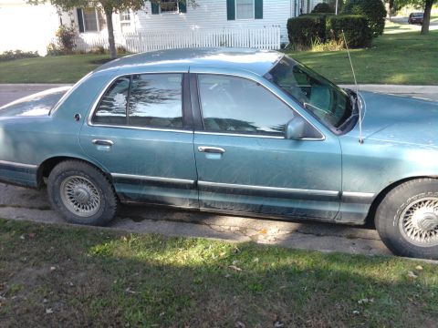 1993 Mercury Grand Marquis - This sedan is parked on the side of the road with grass and a house in the background.
