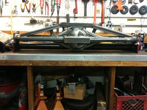 Suzuki Samurai - A custom rear axle assembly with prominent triangulated suspension mounts is displayed on a workbench.