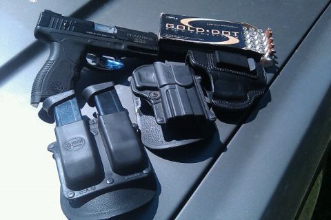 2000 Mercury Grand Marquis - A pistol, spare magazines, and ammunition are laid out on a car's surface.