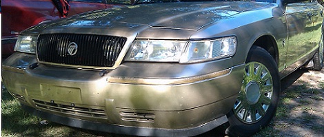 2000 Mercury Grand Marquis - The front of a gold Mercury Grand Marquis is visible, parked next to another vehicle.