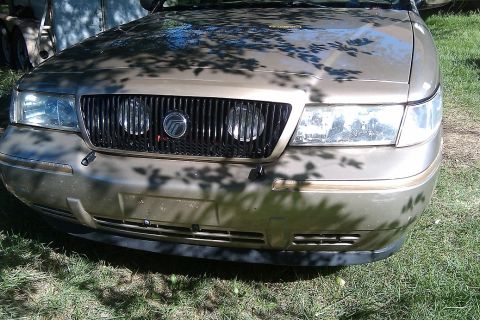 2000 Mercury Grand Marquis - Front view of a gold 2000 Mercury Grand Marquis, highlighting its distinctive grille and headlights.