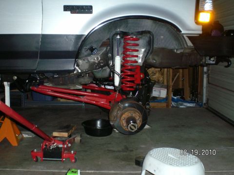 1996 Ford Bronco - The front suspension of a 1996 Ford Bronco is shown with modifications, including red coil springs and new red control arms.