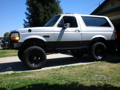 1996 Ford Bronco - Side view of a lifted 1996 Ford Bronco parked in a driveway.