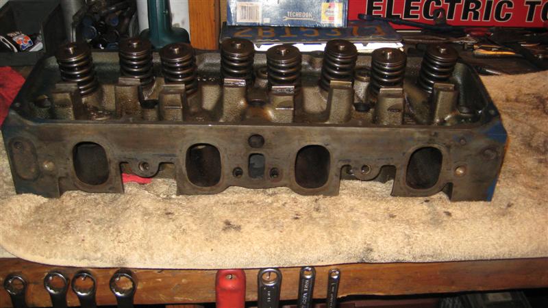 engine cylinder head with valves and springs, sitting on a towel on a workbench