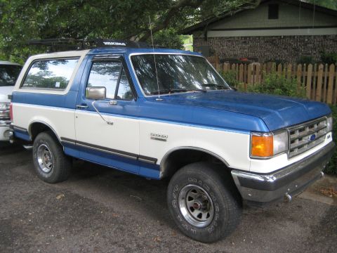 1988 Ford Bronco - Two-tone blue and white 1988 Ford Bronco with a roof rack is parked outside.