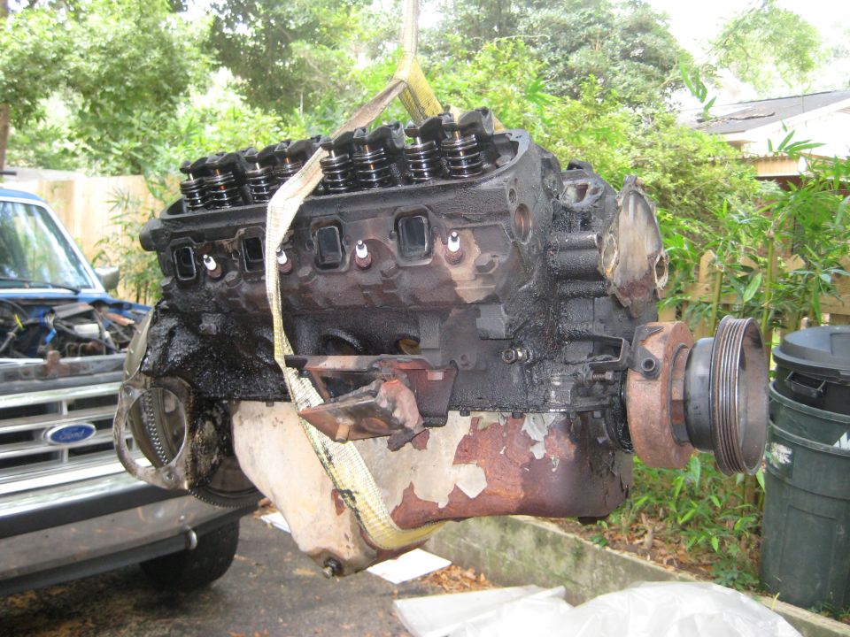 Engine being lifted by a crane, with a blue truck in the background