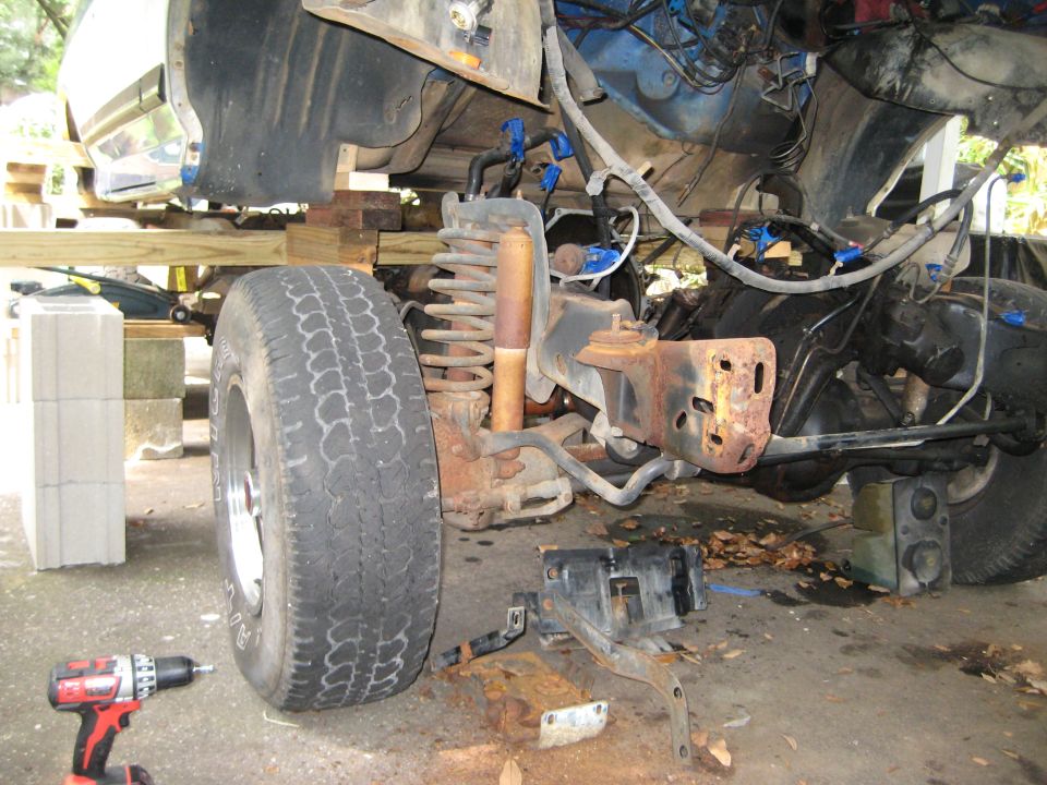 1988 Ford Bronco front suspension and frame components during rebuild, with tire and shock visible