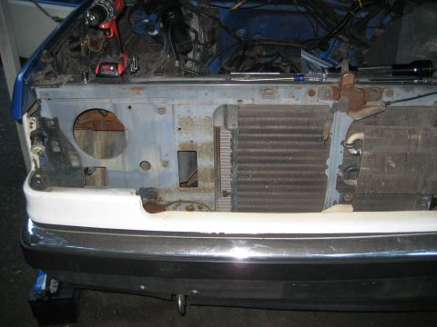 1988 Ford Bronco - The front end of a vehicle is disassembled, revealing the radiator and engine bay for repair work.