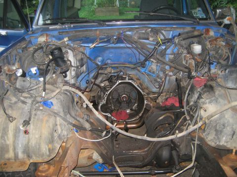 1988 Ford Bronco - The engine bay of a blue vehicle is shown with the transmission removed, revealing the engine block and surrounding components.
