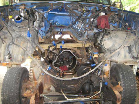 1988 Ford Bronco - The engine bay of a vehicle is shown with the transmission removed, revealing extensive wiring and internal components.