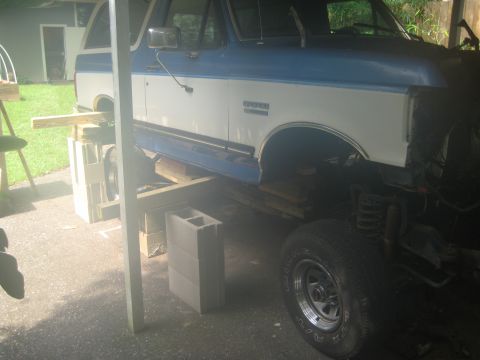 1988 Ford Bronco - This blue and white Ford Bronco is elevated on wooden blocks and cinder blocks for work.