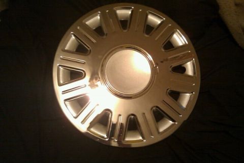 2000 Mercury Grand Marquis - A single chrome hubcap is shown against a dark background.