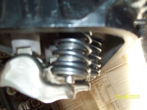 1985 Ford Bronco - Close-up view of engine valve springs and rocker arm assembly, with visible text on a cardboard box in the background.
