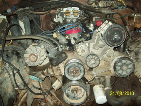 1985 Ford Bronco - Close-up view of a V8 engine bay, showing the carburetor, distributor, and various belts and pulleys.