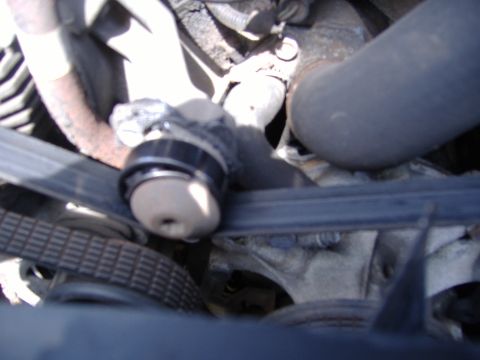 1995 Ford F-150 - Close-up view of engine components, including a belt and pulley system, with visible hoses and metal parts.