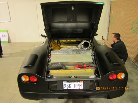 1996 Ford Bronco - A black sports car is shown from the rear with its engine compartment open, displaying the engine and components.