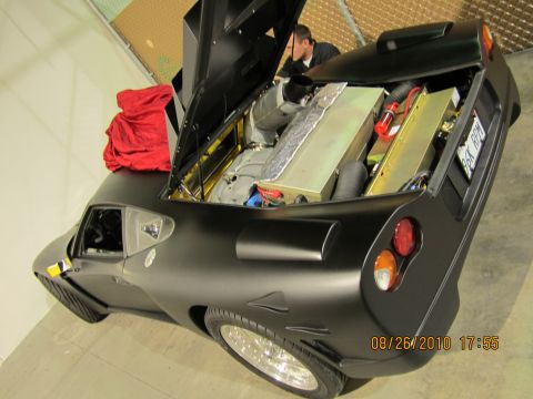 1996 Ford Bronco - Custom sports car's rear engine bay is open, revealing its internal components and a red cloth on the hood.