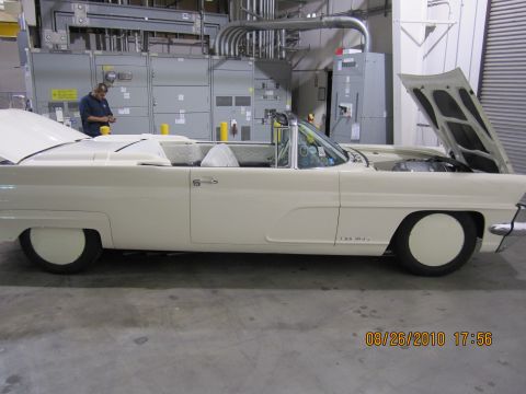 1996 Ford Bronco - A white convertible is parked indoors with its hood open, showing the engine compartment.