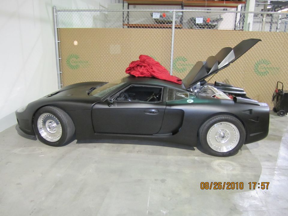 Black sports car with hood and trunk open, red tarp on roof