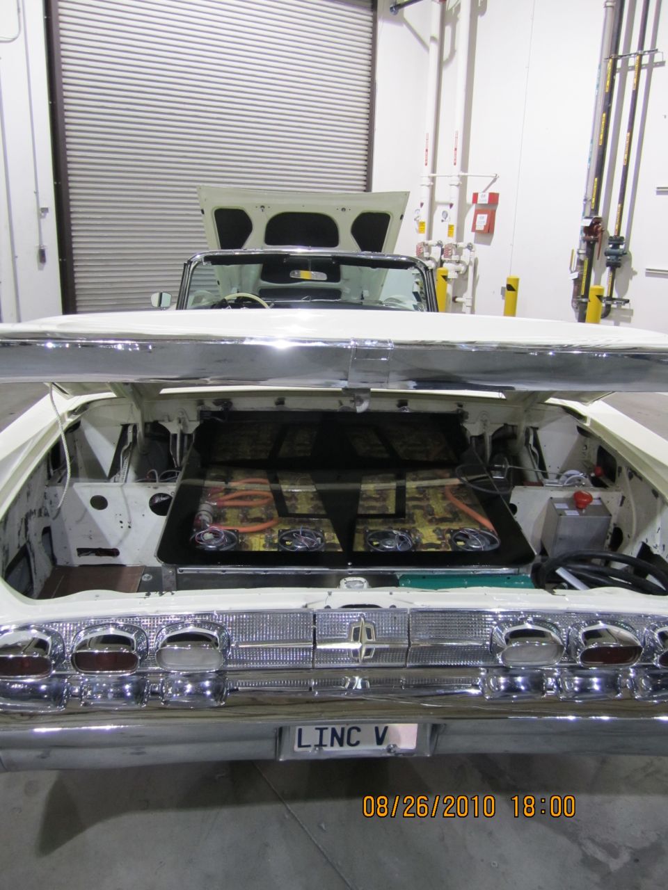 White convertible with open trunk showing custom interior and chrome bumper with 'LINC V' plate