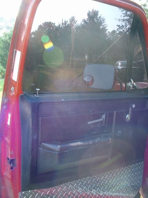 1994 GMC Suburban - View of the interior door panel of a red truck, diamond plate trim on the lower section.