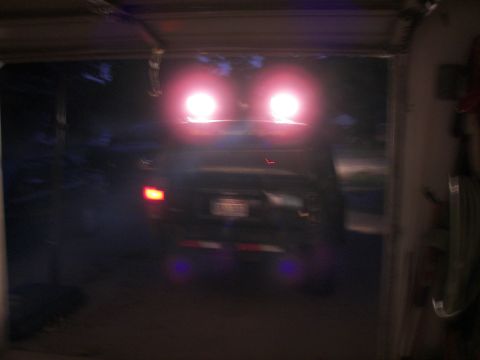 1988 Ford Bronco - A dark SUV is seen exiting a garage, its bright headlights and taillights illuminated.
