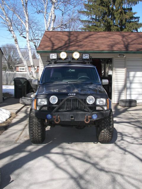 1988 Ford Bronco - Front view of a modified Jeep Cherokee with off-road tires and auxiliary lights.