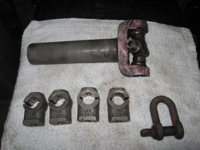 Driveshaft yoke with U-joint, four clamp yokes stamped C2AE 4531-B, and a shackle on a white towel