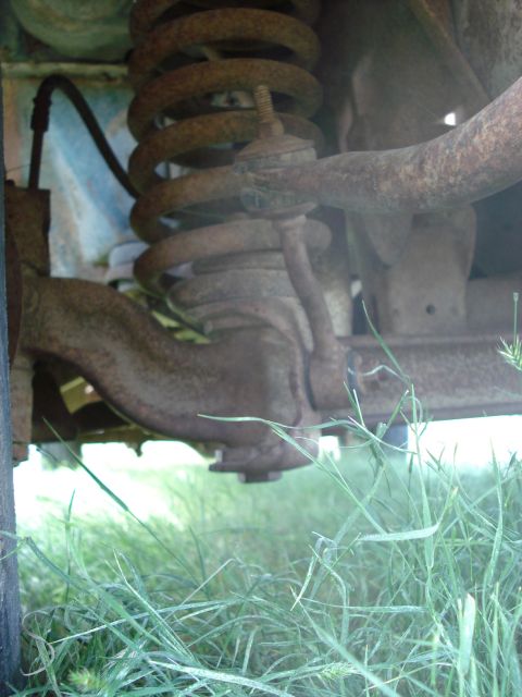 1979 Ford F-150 - Close-up view of heavily rusted front suspension parts, including a coil spring and control arm.